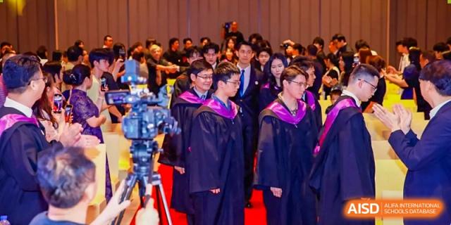 A group of Zhuhai Oriental Yinghua International Academy students in graduation gowns standing together in a formal setting.