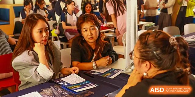 A female faculty member or admissions representative at a desk during an event at Zhuhai Oriental Yinghua International Academy.