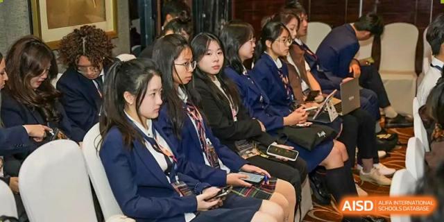 Female students from Zhuhai Oriental Yinghua International Academy sitting in an audience and listening intently at an event.