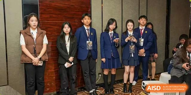 Two male and three female students from Zhuhai Oriental Yinghua International Academy standing together in their school uniforms.