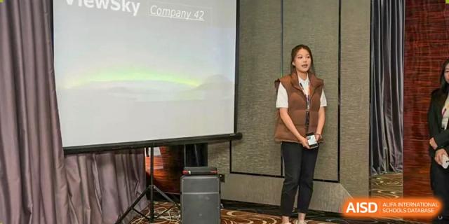 A teacher or staff member from Zhuhai Oriental Yinghua International Academy presenting in front of a projection screen during an event.
