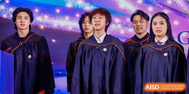 Two male students from Zhuhai Oriental Yinghua International Academy in graduation gowns standing on a stage.
