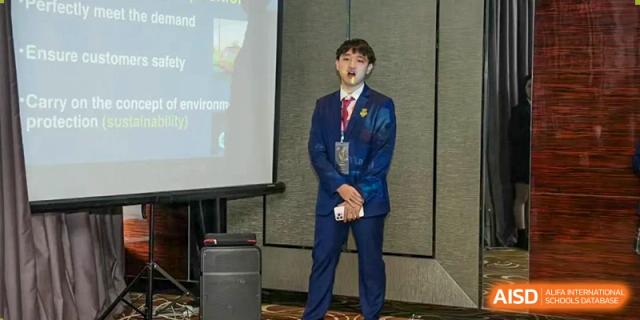 A male student from Zhuhai Oriental Yinghua International Academy in a suit standing on a stage at an event.