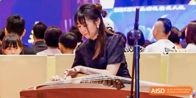 A female student from Zhuhai Oriental Yinghua International Academy reviewing documents or brochures at a table.