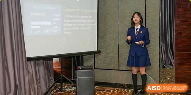 A presenter at Zhuhai Oriental Yinghua International Academy speaking in front of a projection screen with visible text.