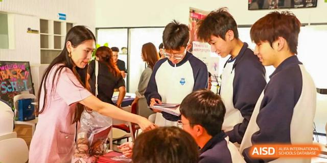 Students from Zhuhai Oriental Yinghua International Academy gathered around a table with a staff member at a busy event.