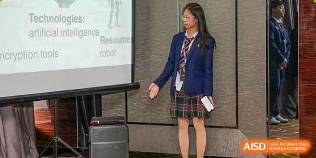 A female student from Zhuhai Oriental Yinghua International Academy in uniform giving a presentation about a robot resource.