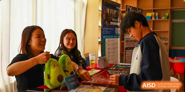 A female student from Zhuhai Oriental Yinghua International Academy speaking with an adult at an information booth.