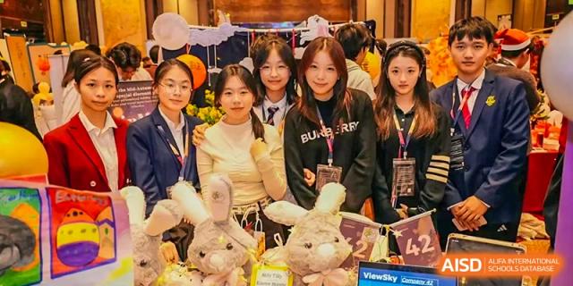 A group of female students from Zhuhai Oriental Yinghua International Academy posing with stuffed animals at an event booth.