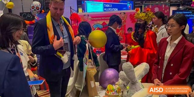 Students from Zhuhai Oriental Yinghua International Academy gathered around a colorful event booth with balloons and items.