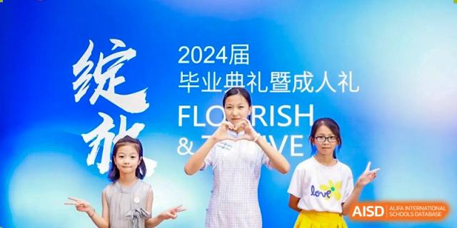 A student from Zhuhai Oriental Yinghua International Academy making a heart shape with her hands in front of a 2024 graduation ceremony banner.