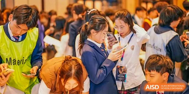 A female student from Zhuhai Oriental Yinghua International Academy looking at her mobile phone while standing with others.