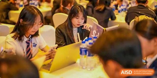 A female student from Zhuhai Oriental Yinghua International Academy focused on her work at a table with a water bottle and papers.