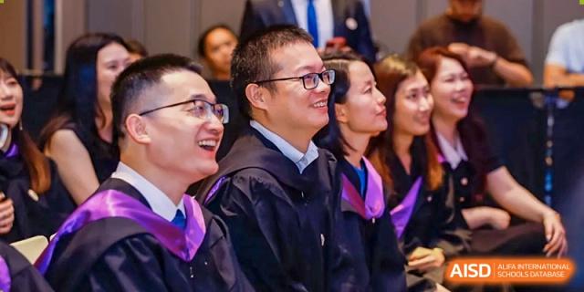 Faculty and staff members from Zhuhai Oriental Yinghua International Academy smiling while attending a school ceremony or event.
