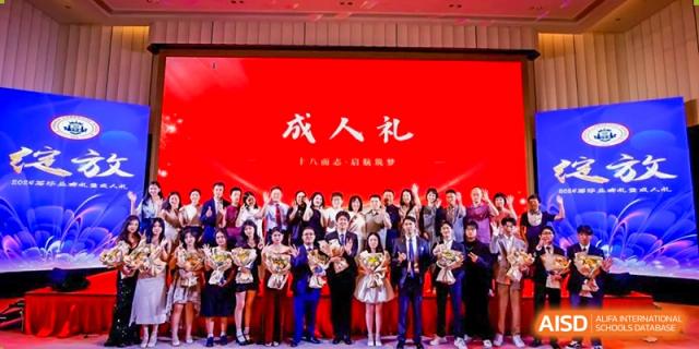 A group photo of students and staff from Zhuhai Oriental Yinghua International Academy in formal wear against a red background that says "成人礼" (Coming of Age Ceremony).