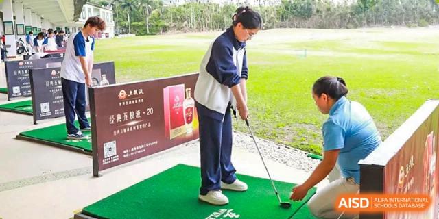 A female student from Zhuhai Oriental Yinghua International Academy practicing a golf swing at a driving range.