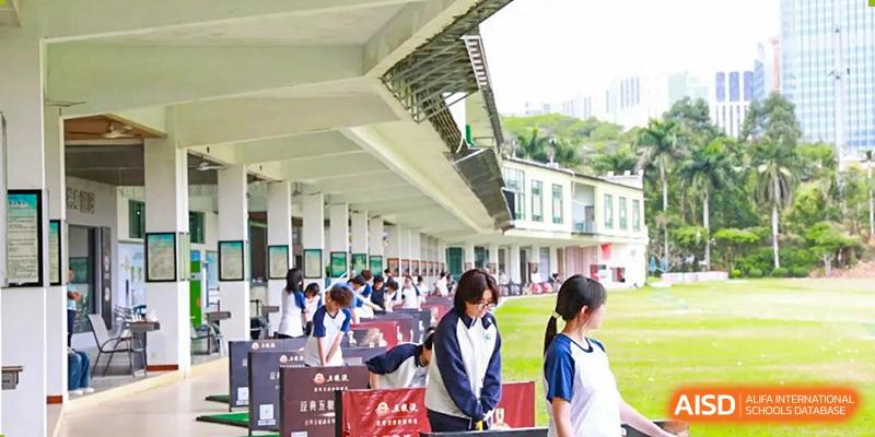 Students from Zhuhai Oriental Yinghua International Academy practicing their golf swings at an outdoor covered range.