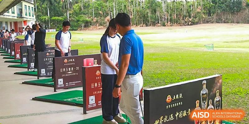 A close-up view of a golf instructor assisting a student from Zhuhai Oriental Yinghua International Academy with their stance at the driving range.
