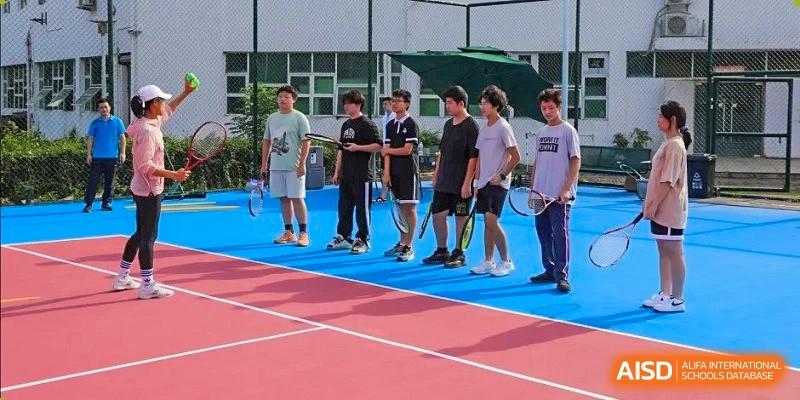 A group of male students from Zhuhai Oriental Yinghua International Academy standing on a tennis or basketball court for a sports activity or instruction.