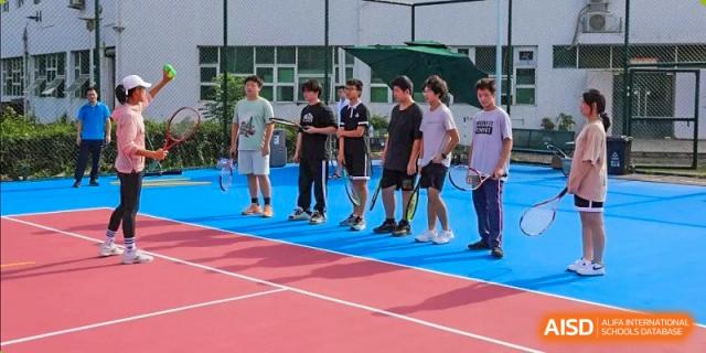 A group of male students from Zhuhai Oriental Yinghua International Academy standing on a tennis or basketball court for a sports activity or instruction.