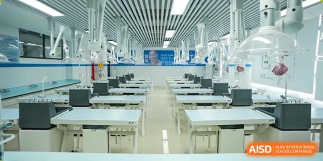 An interior shot of a modern, bright laboratory or specialized skills room, with many white desks and dental/medical practice equipment lined up at Changjun Bilingual School Of Changsha City.