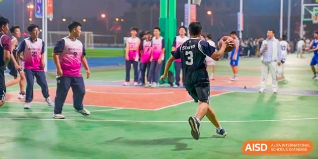 A student from Changjun Bilingual School Of Changsha City wearing a black jersey and running on a red track during a sports activity.