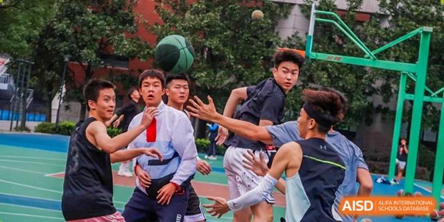 A close-up action moment of students from Changjun Bilingual School Of Changsha City playing a competitive basketball game outdoors.