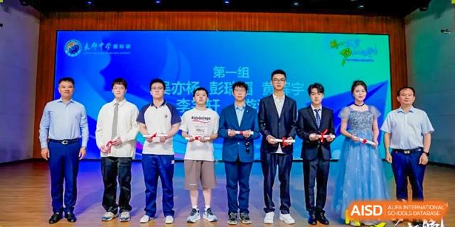 Students and staff from Changjun Bilingual School Of Changsha City standing on a stage during an awards ceremony, holding trophies.