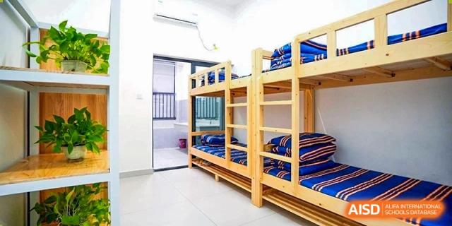 An interior shot of a clean, bright dormitory room at Changjun Bilingual School Of Changsha City with wooden bunk beds.