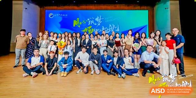 Group of students and staff from Changjun Bilingual School Of Changsha City posing together on a stage floor in front of a graduation banner.