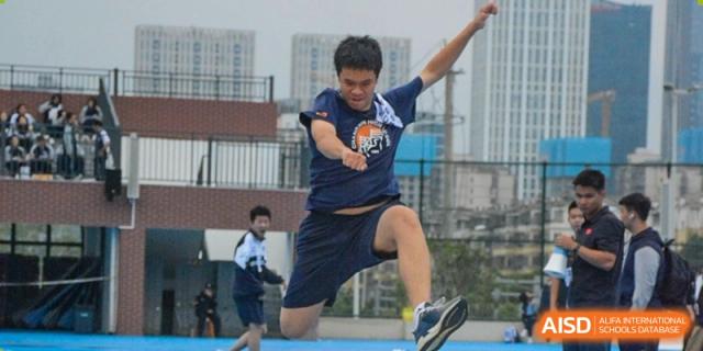 A student from Changjun Bilingual School Of Changsha City captured leaping outdoors during a long jump or sports drill.
