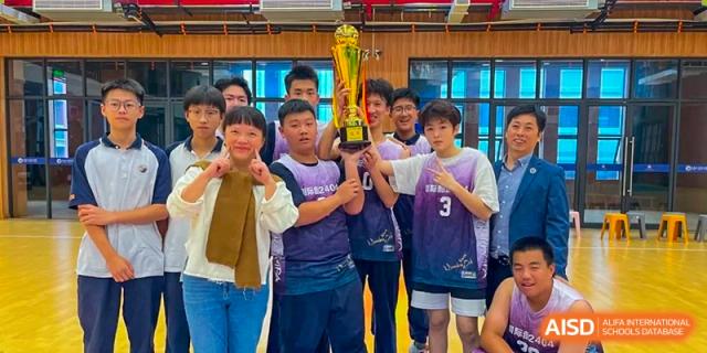 A group of male students in casual clothes and sports jerseys are posing together indoors, smiling for a photograph at Changjun Bilingual School Of Changsha City.