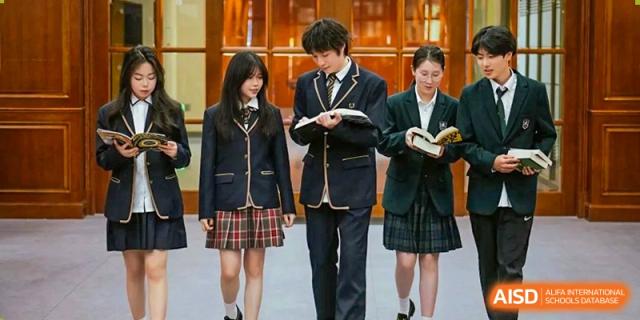 Four students from Cogdel Cranleigh High School, dressed in school uniforms, standing and looking at textbooks.