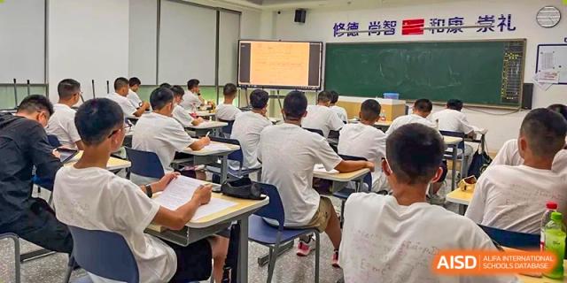 View from the back of a classroom at Cogdel Cranleigh High School, showing students seated at desks facing a screen and a blackboard.