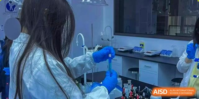 A student or teacher from Cogdel Cranleigh High School, wearing blue gloves, conducting a scientific experiment in a laboratory.
