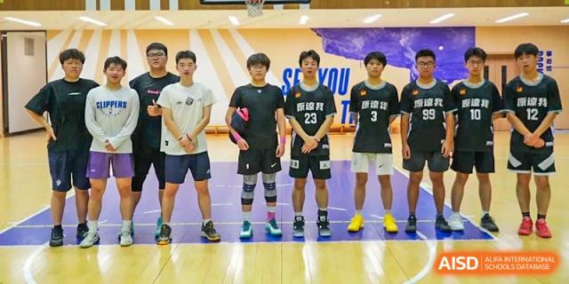 A Cogdel Cranleigh High School basketball team standing in a line for a group photo on the court, with students wearing various jerseys, including numbers 23 and 3.