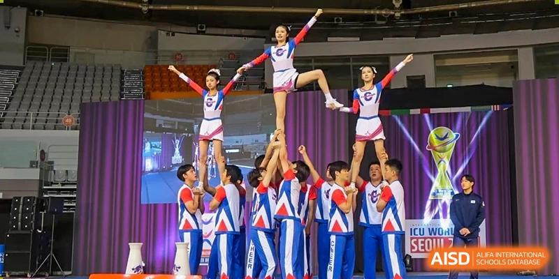 Cheerleading or acrobatic team from Cogdel Cranleigh High School performing a pyramid formation on a stage.