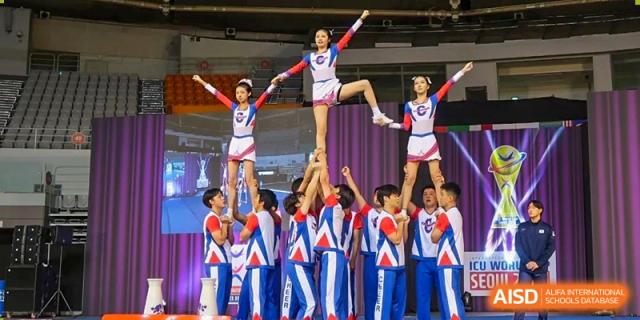 Cheerleading or acrobatic team from Cogdel Cranleigh High School performing a pyramid formation on a stage.