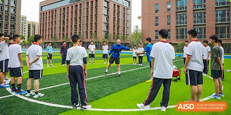 Students of Cogdel Cranleigh High School participating in a physical education class or sports practice on an outdoor turf field.