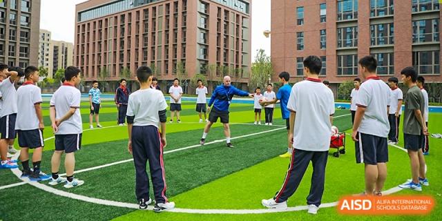 Students of Cogdel Cranleigh High School participating in a physical education class or sports practice on an outdoor turf field.