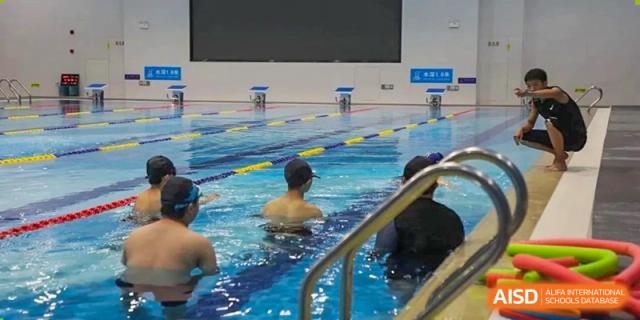 Close-up view of students swimming laps in the lanes of an indoor swimming pool at Cogdel Cranleigh High School.