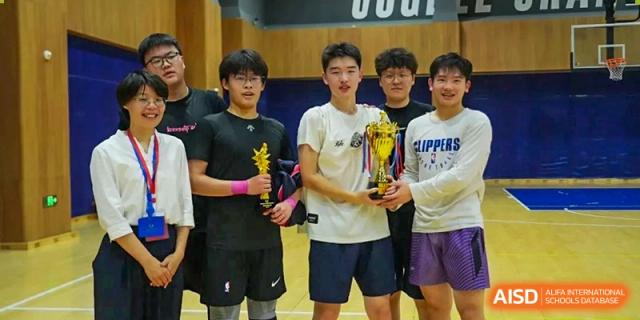 Four male students from Cogdel Cranleigh High School, one holding a trophy, celebrating a sports victory.