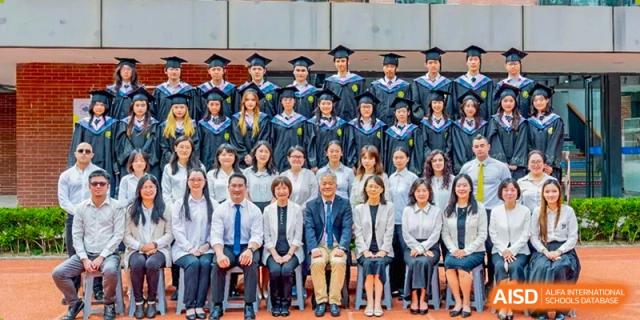 A group photo of graduates in gowns and school faculty and staff seated in the front at Fudan International School.