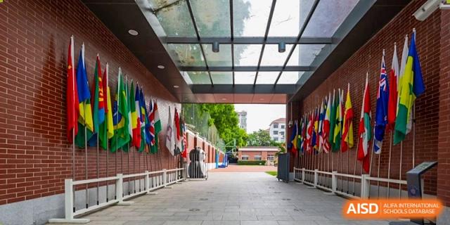 The exterior walkway or corridor of Fudan International School, lined with various international flags.