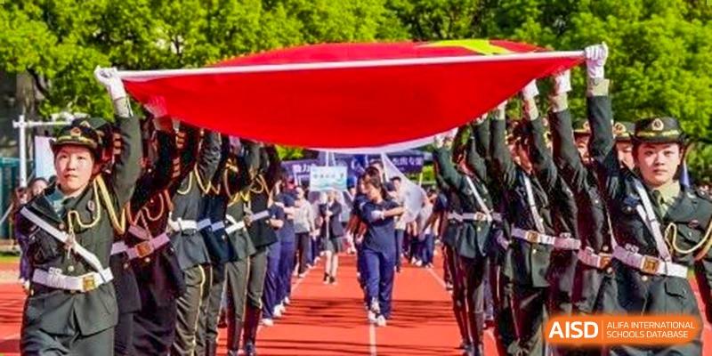 Fudan International School students in uniform marching or participating in a parade on the running track during a school event.