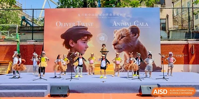 Fudan International School students performing a musical or play ("Oliver Twist" poster visible) on an outdoor stage.
