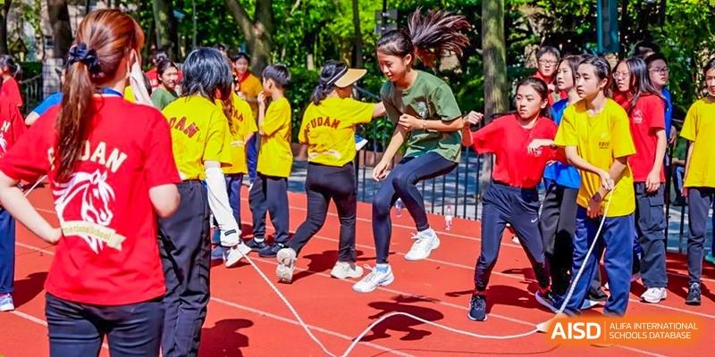 Fudan International School students participating in a dynamic jump-rope or skipping relay race on the track.