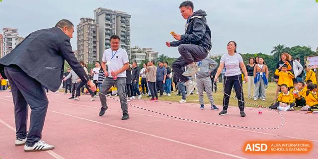 A male student from Humen Foreign Language School International Division jumps high while participating in a rope-skipping event on a red outdoor track.