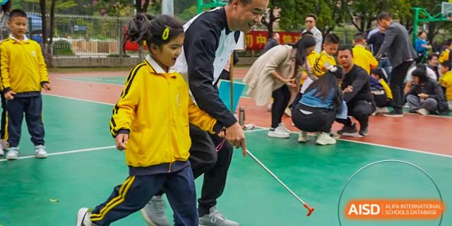 Students from Humen Foreign Language School International Division in yellow jackets participate in a race or activity involving a long pole.