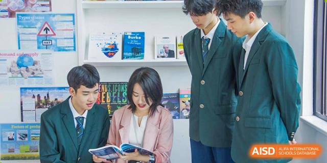 A small group of Maple Glory Education students discussing books in a study area with bookshelves.